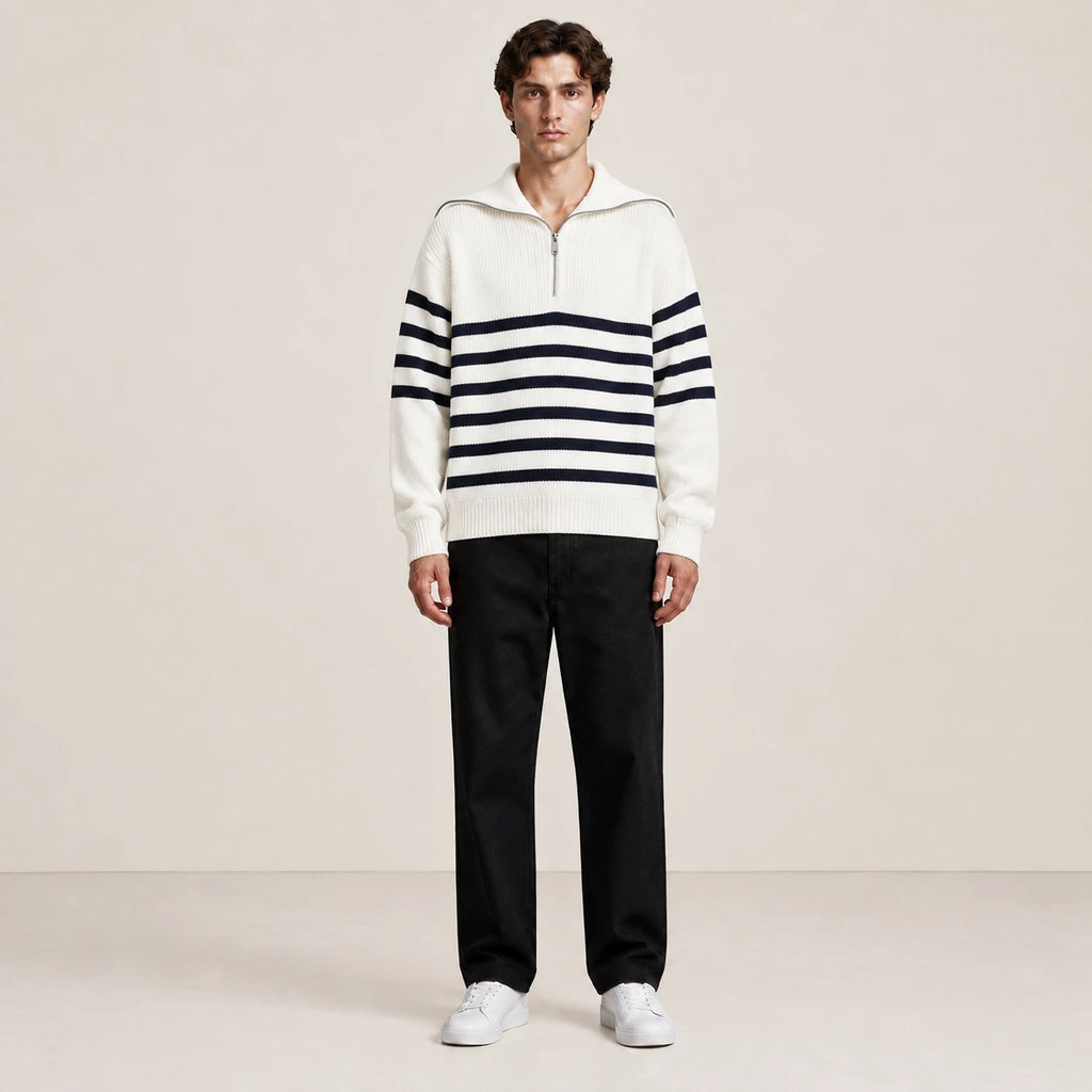 Pull rayé blanc et noir à col zippé porté de face dans le studio IVAREE.