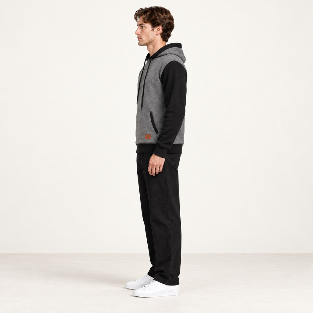 Sweat à capuche color-block gris et noir, vu de profil dans le studio IVAREE.