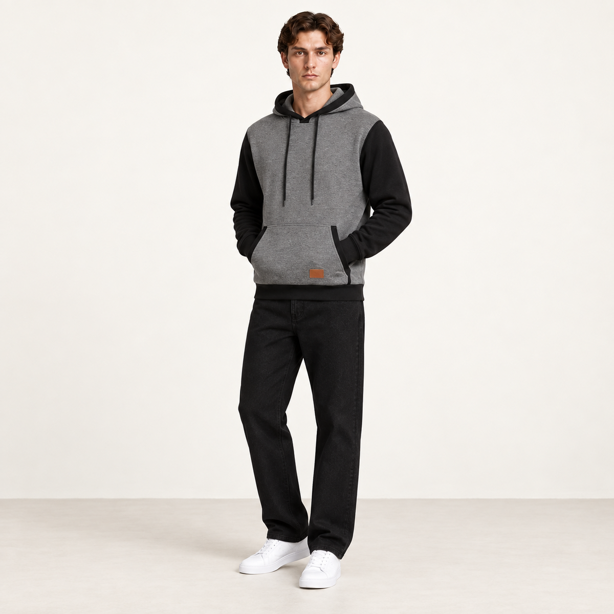 Sweat à capuche color-block gris et noir, porté de trois-quarts dans le studio IVAREE.