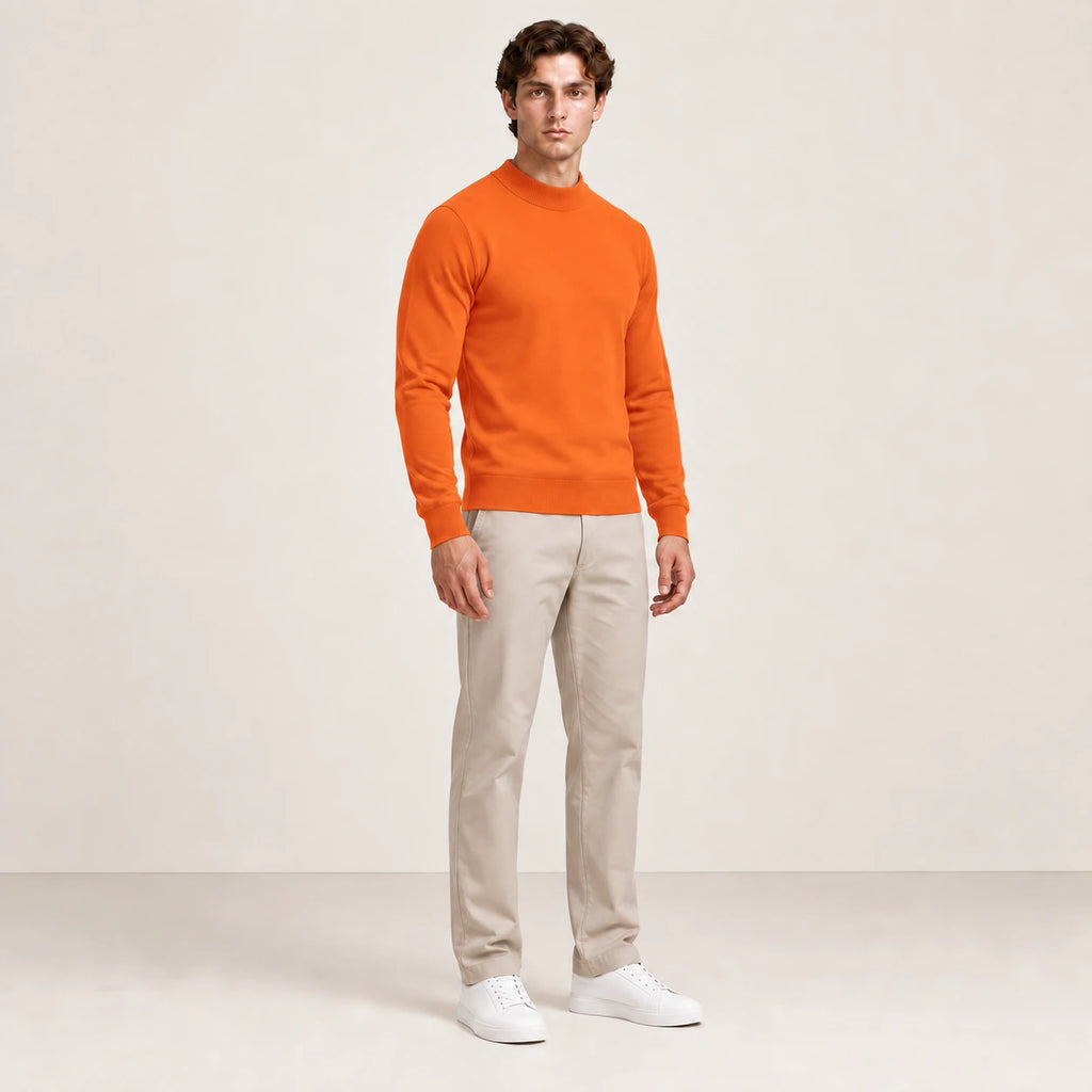 Sweat uni orange à col légèrement montant, porté de trois-quarts dans le studio IVAREE.