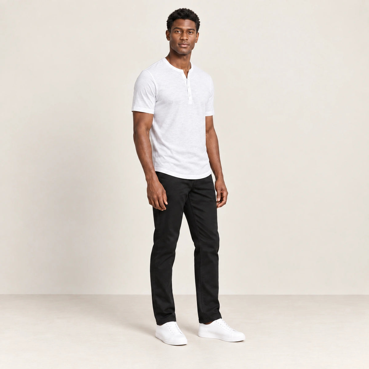 T-shirt blanc à col Henley boutonné, porté de trois-quarts dans le studio IVAREE.