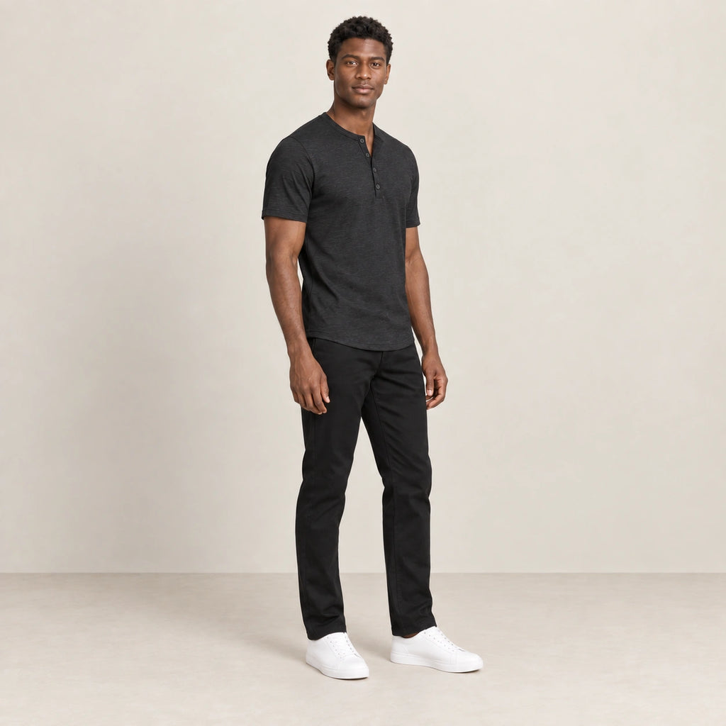 T-shirt noir à col Henley boutonné, porté de trois-quarts dans le studio IVAREE.