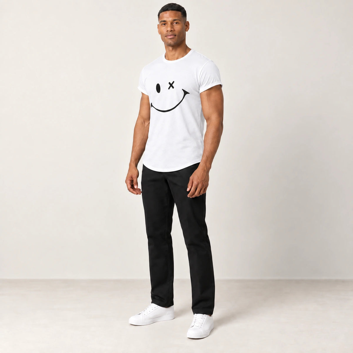 T-shirt en coton blanc à col rond et motif sourire, porté de trois-quarts dans le studio IVAREE.