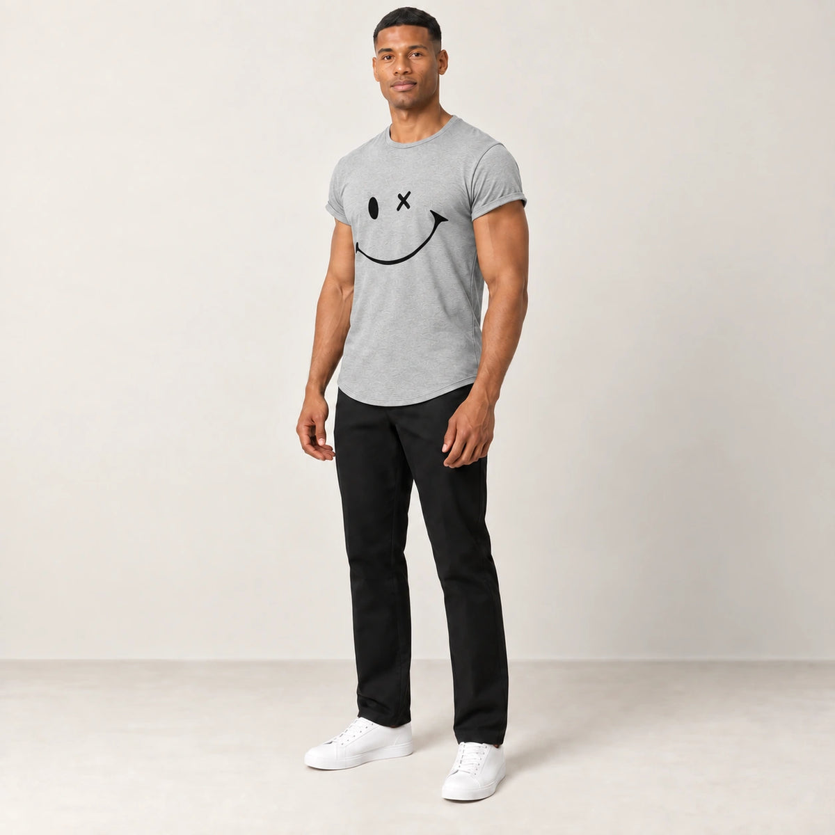 T-shirt en coton gris à col rond et motif sourire, porté de trois-quarts dans le studio IVAREE.