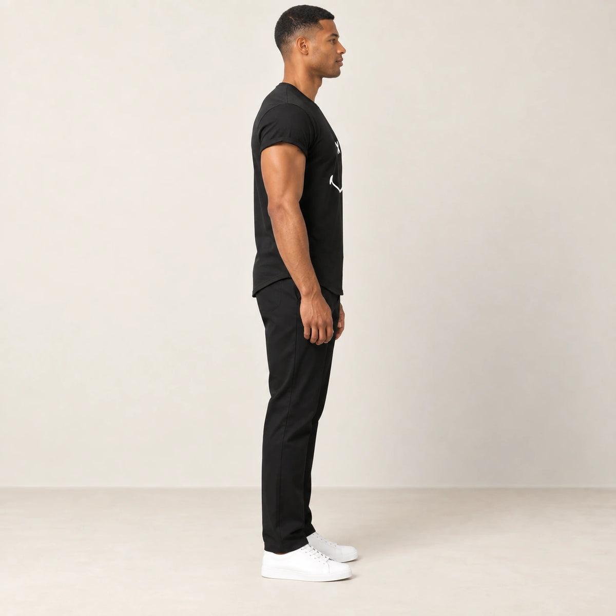 T-shirt en coton noir à col rond et motif sourire, vue de profil dans le studio IVAREE.