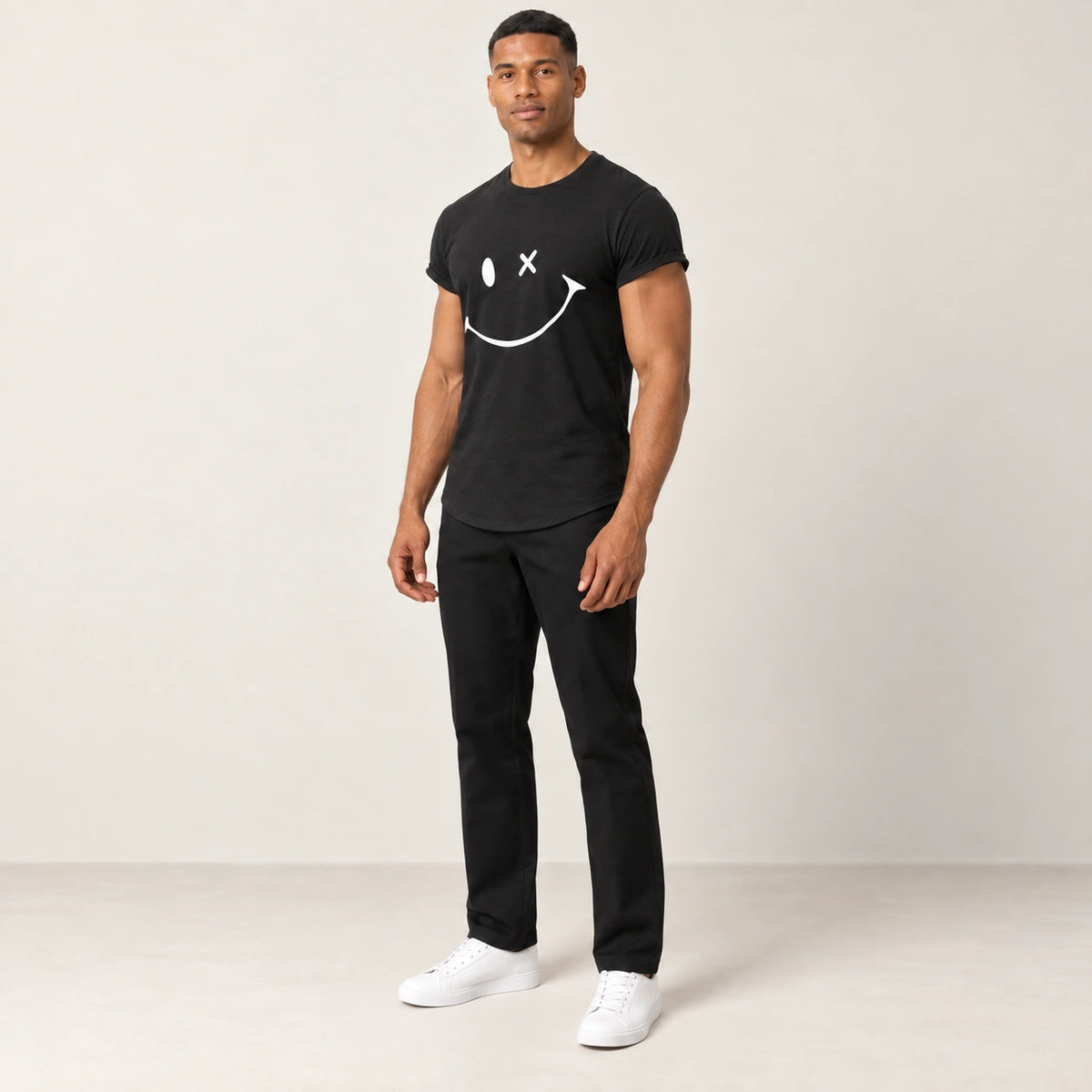 T-shirt en coton noir à col rond et motif sourire, porté de trois-quarts dans le studio IVAREE.