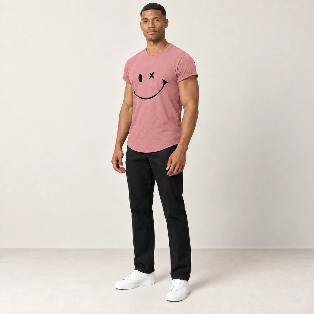 T-shirt en coton rose à col rond et motif sourire, porté de trois-quarts dans le studio IVAREE.