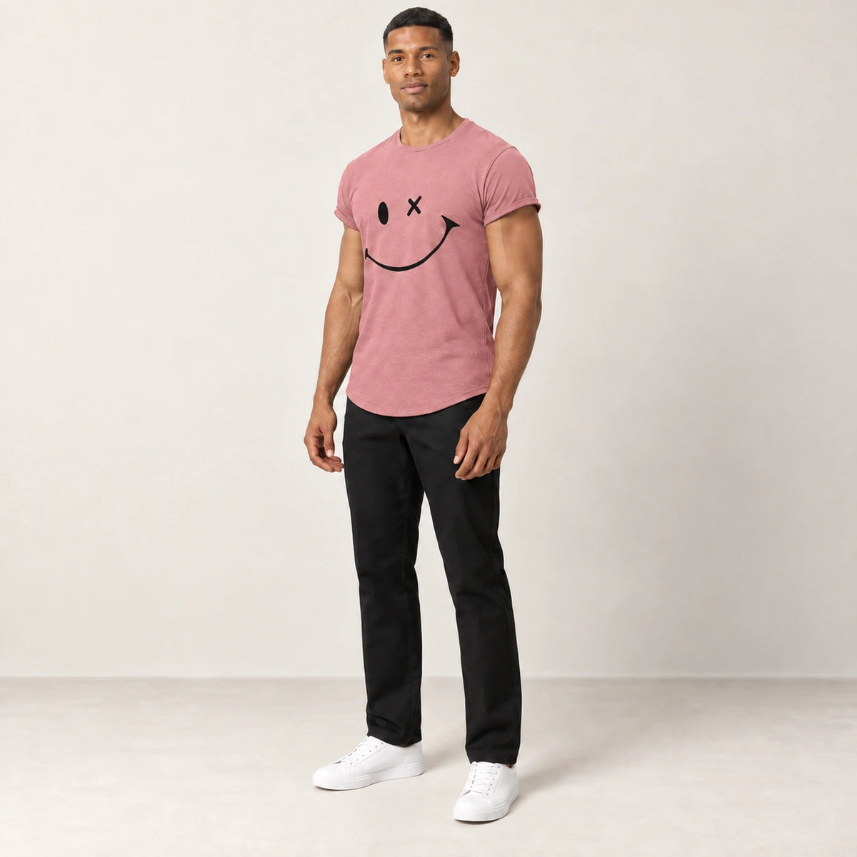 T-shirt en coton rose à col rond et motif sourire, porté de trois-quarts dans le studio IVAREE.