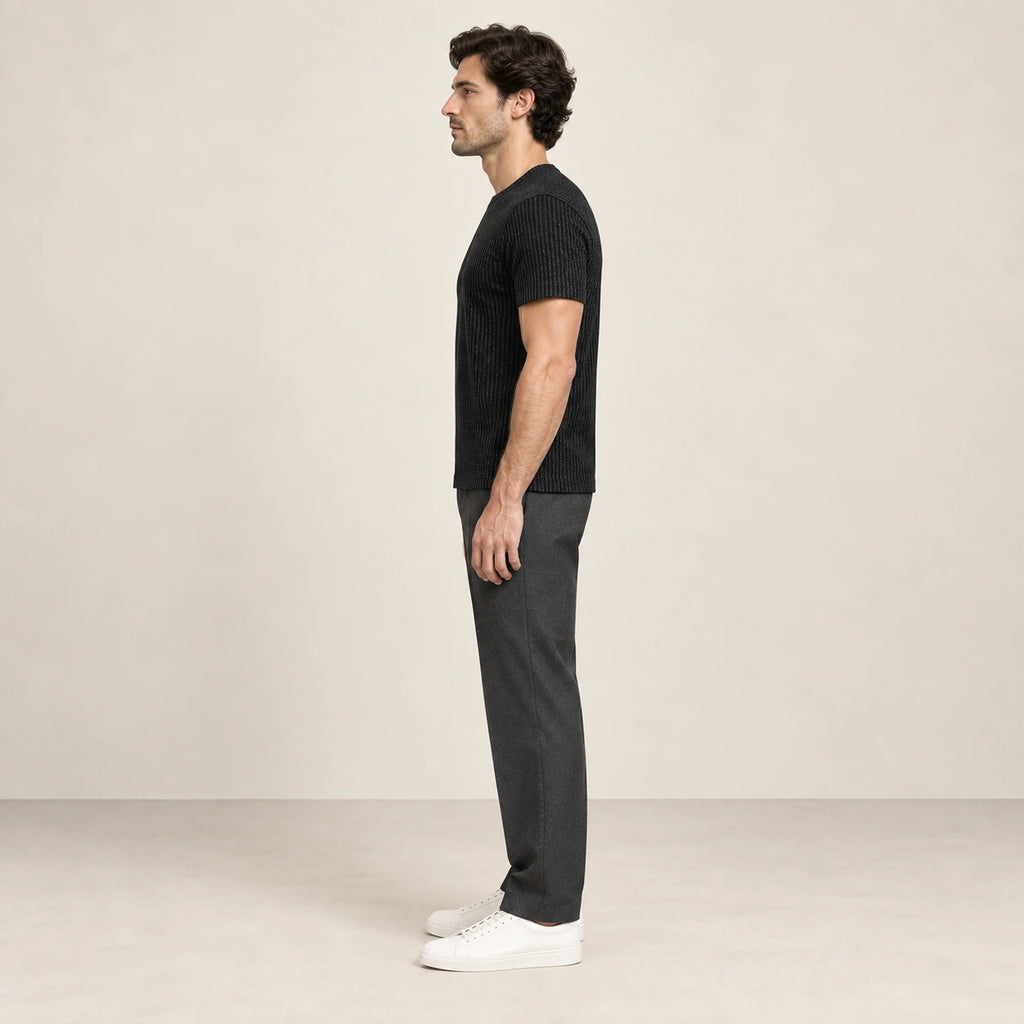 T-shirt noir en maille jacquard à fines lignes verticales, porté de profil dans le studio IVAREE.
