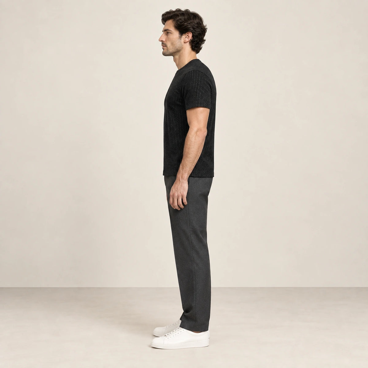T-shirt noir en maille jacquard à fines lignes verticales, porté de profil dans le studio IVAREE.