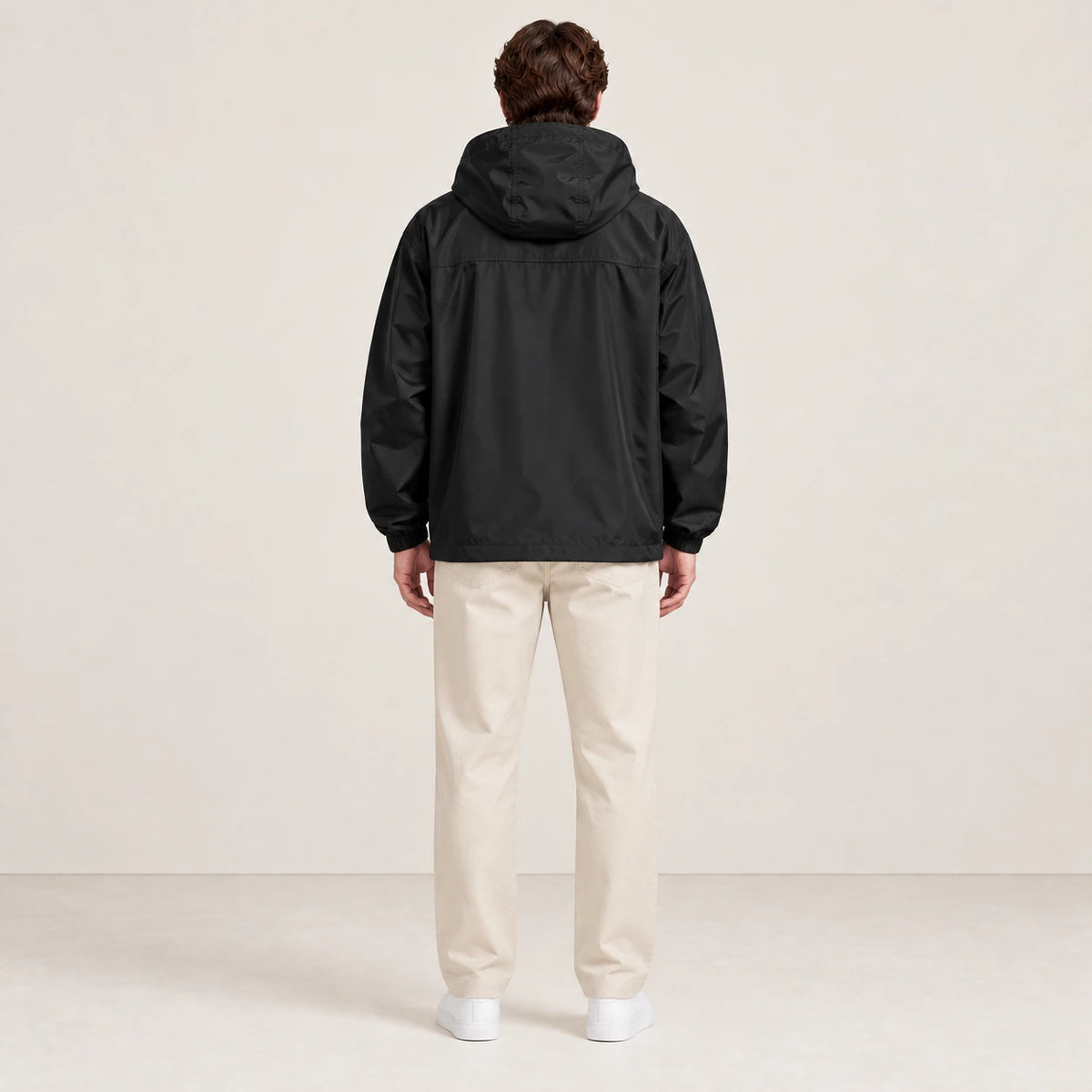 Veste à capuche noire portée de dos dans le studio IVAREE.