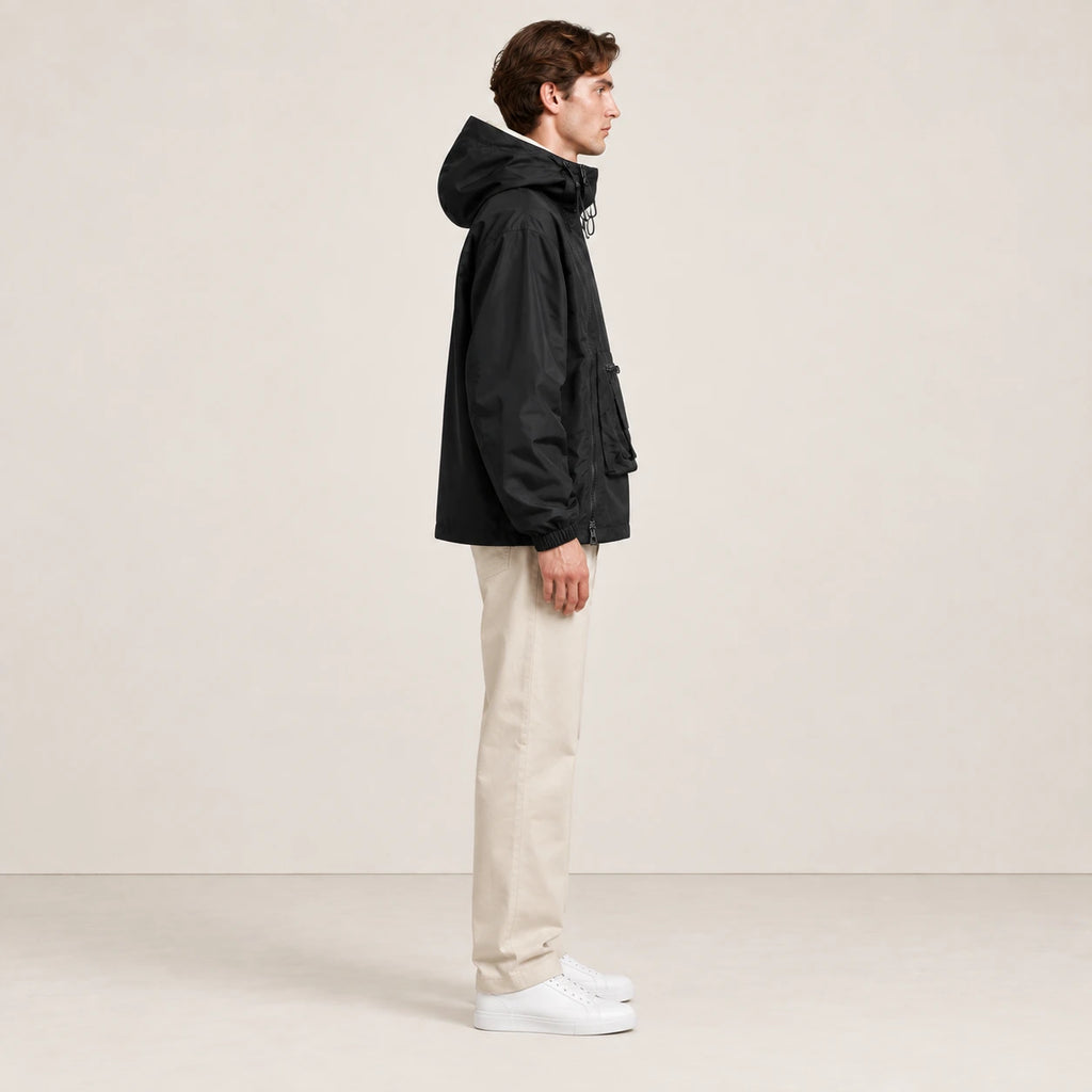 Veste à capuche noire portée de profil dans le studio IVAREE.