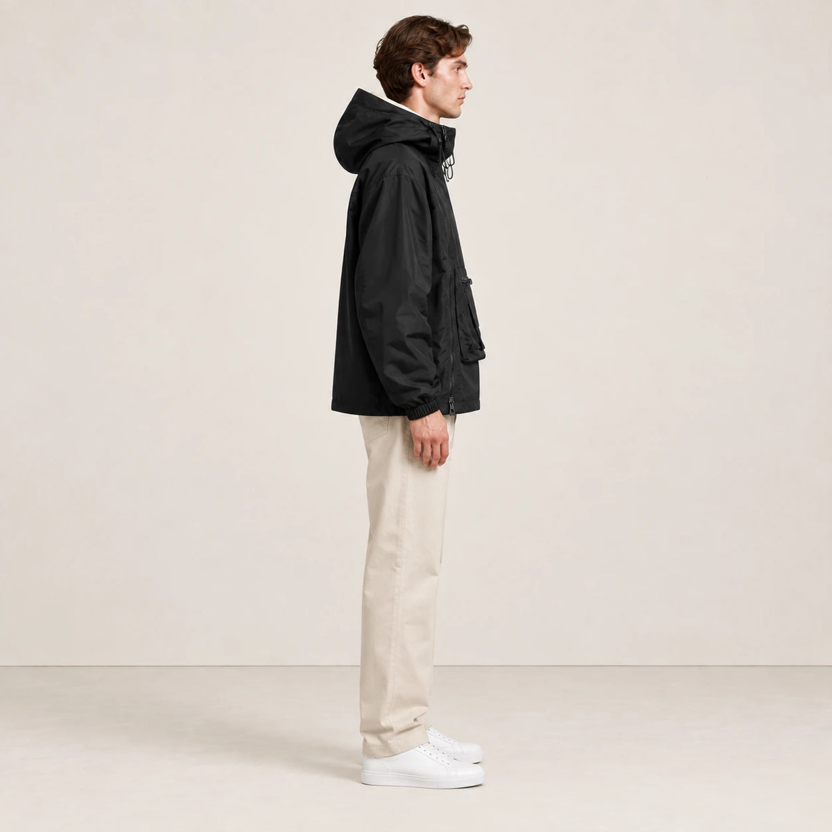 Veste à capuche noire portée de profil dans le studio IVAREE.