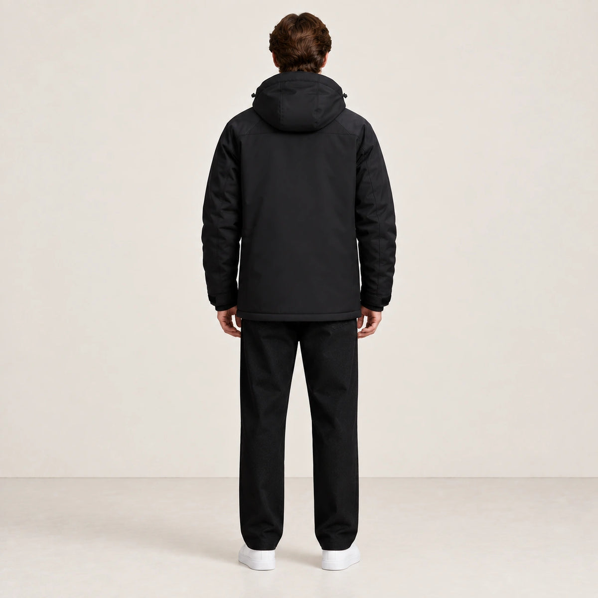 Veste d’hiver technique multipoche noire, portée de dos dans le studio IVAREE.