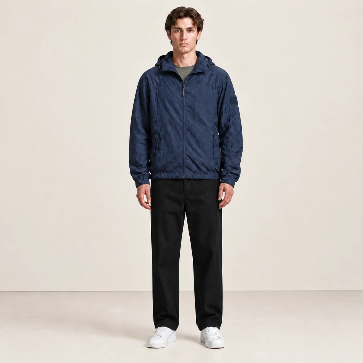 Veste légère bleu marine à capuche et fermeture zippée, portée de face dans le studio IVAREE.