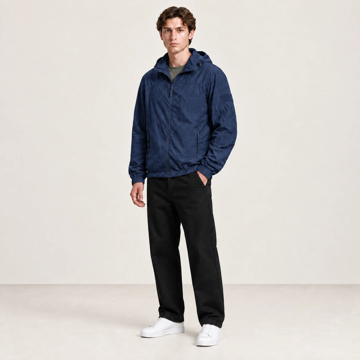 Veste légère bleu marine à capuche et fermeture zippée, portée de trois-quarts dans le studio IVAREE.