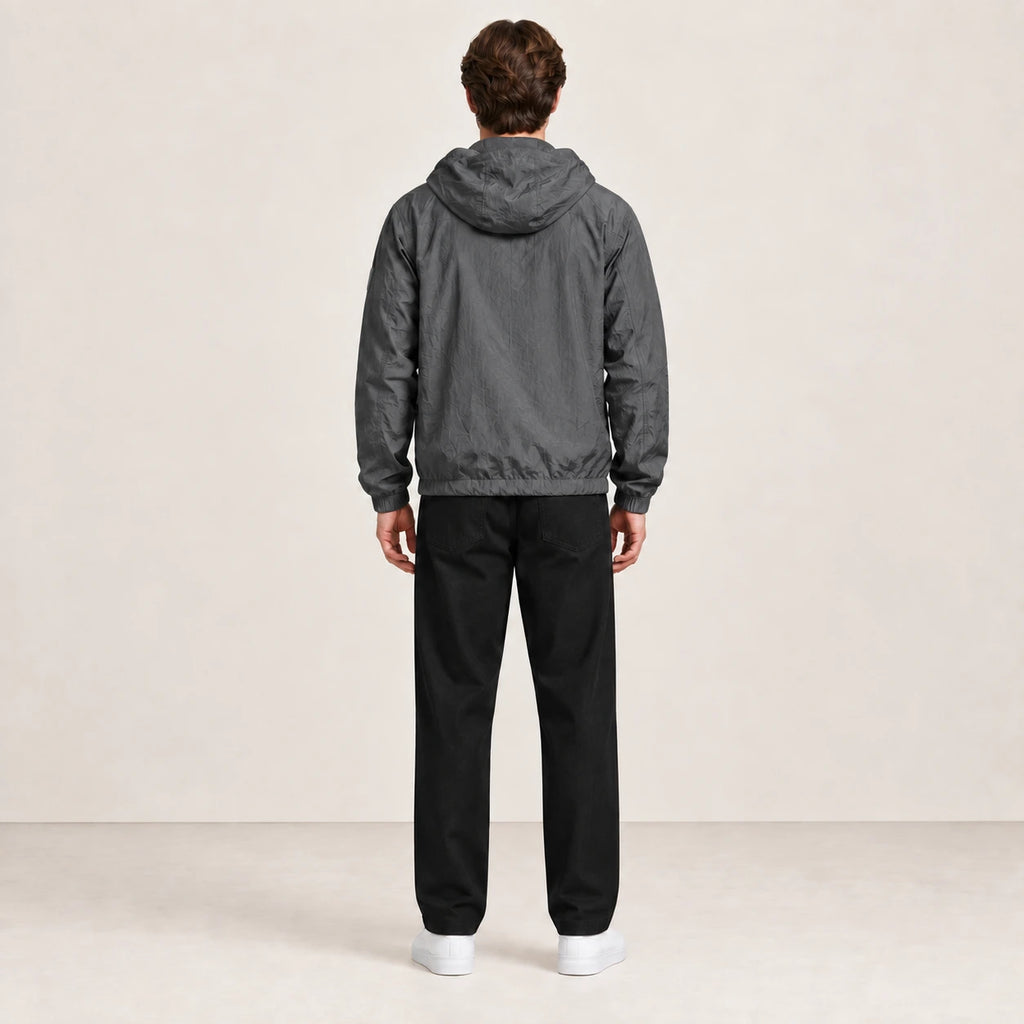 Veste légère gris anthracite à capuche, portée de dos dans le studio IVAREE.