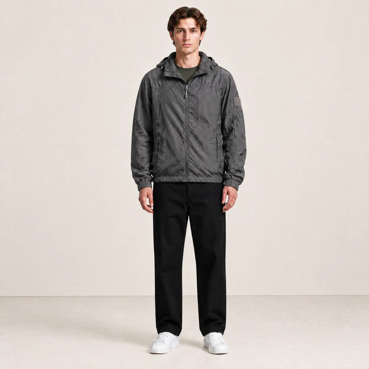 Veste légère gris anthracite à capuche et fermeture zippée, portée de face dans le studio IVAREE.