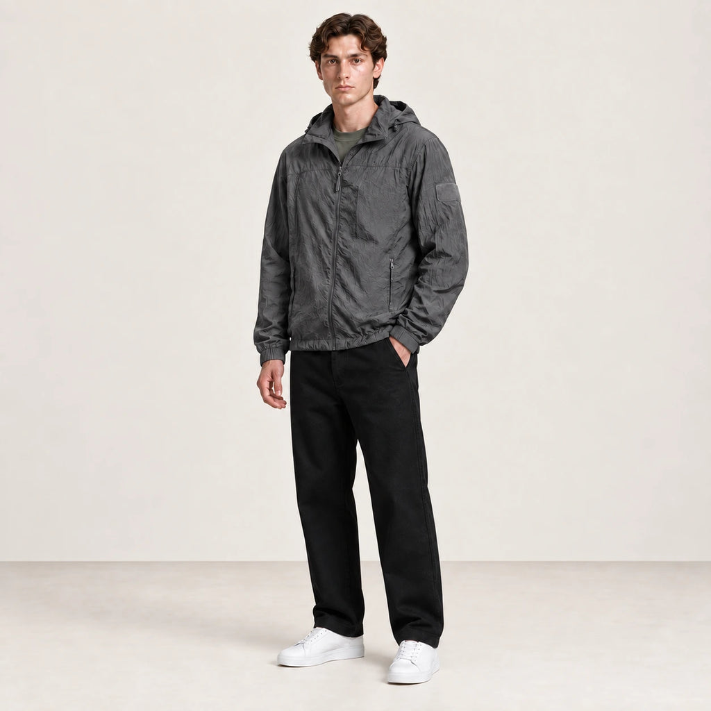 Veste légère gris anthracite à capuche et fermeture zippée, portée de trois-quarts dans le studio IVAREE.