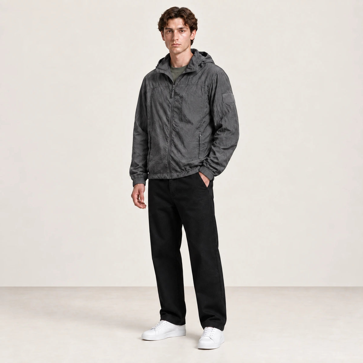 Veste légère gris anthracite à capuche et fermeture zippée, portée de trois-quarts dans le studio IVAREE.