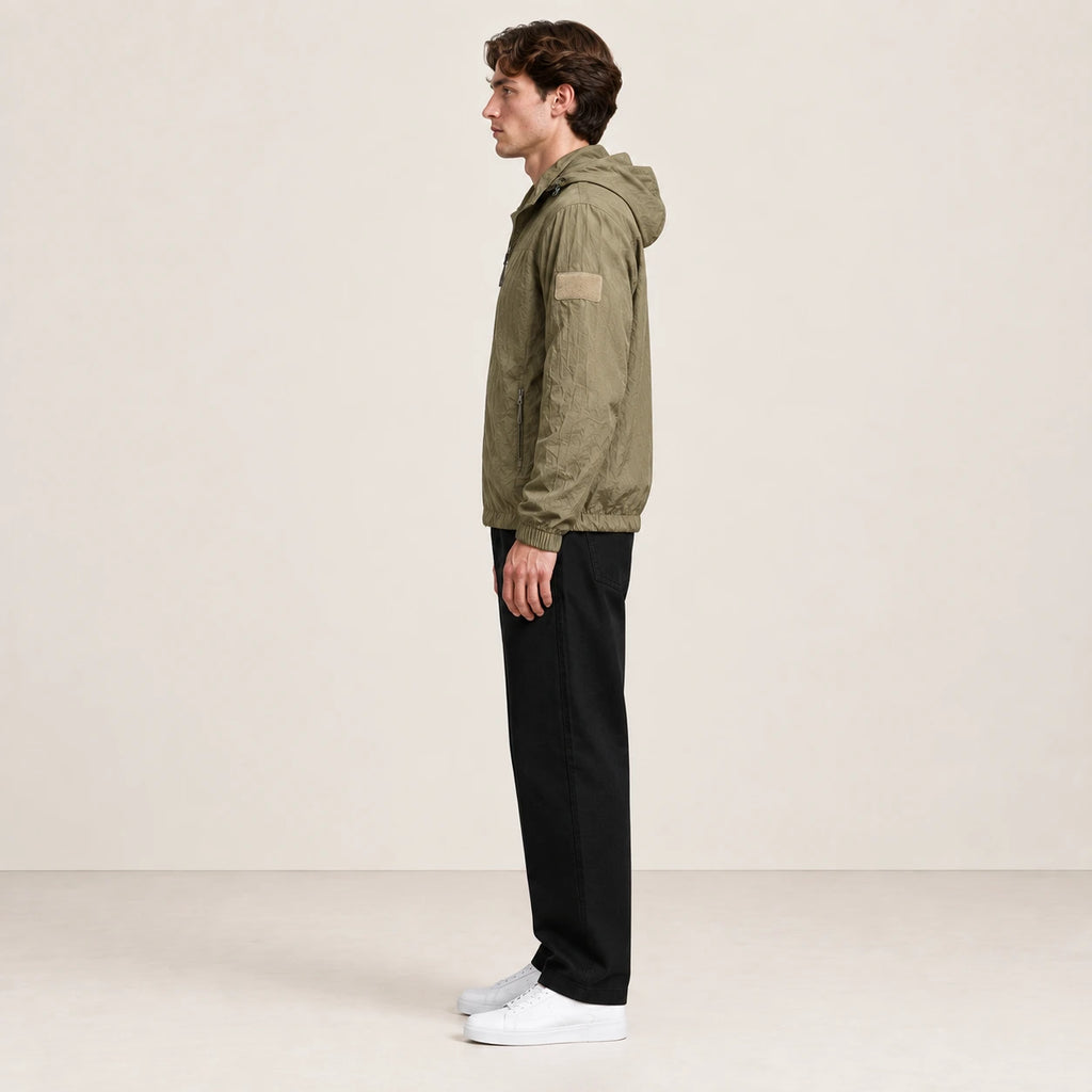 Veste légère kaki à capuche et fermeture zippée, portée de profil dans le studio IVAREE.