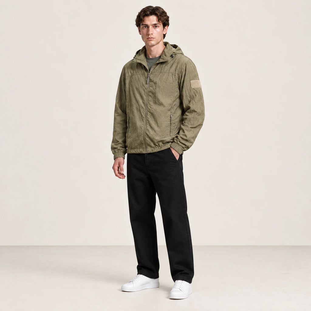 Veste légère kaki à capuche et fermeture zippée, portée de trois-quarts dans le studio IVAREE.