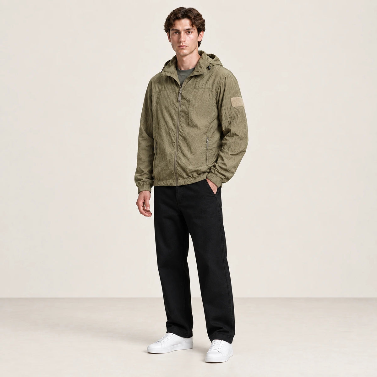 Veste légère kaki à capuche et fermeture zippée, portée de trois-quarts dans le studio IVAREE.