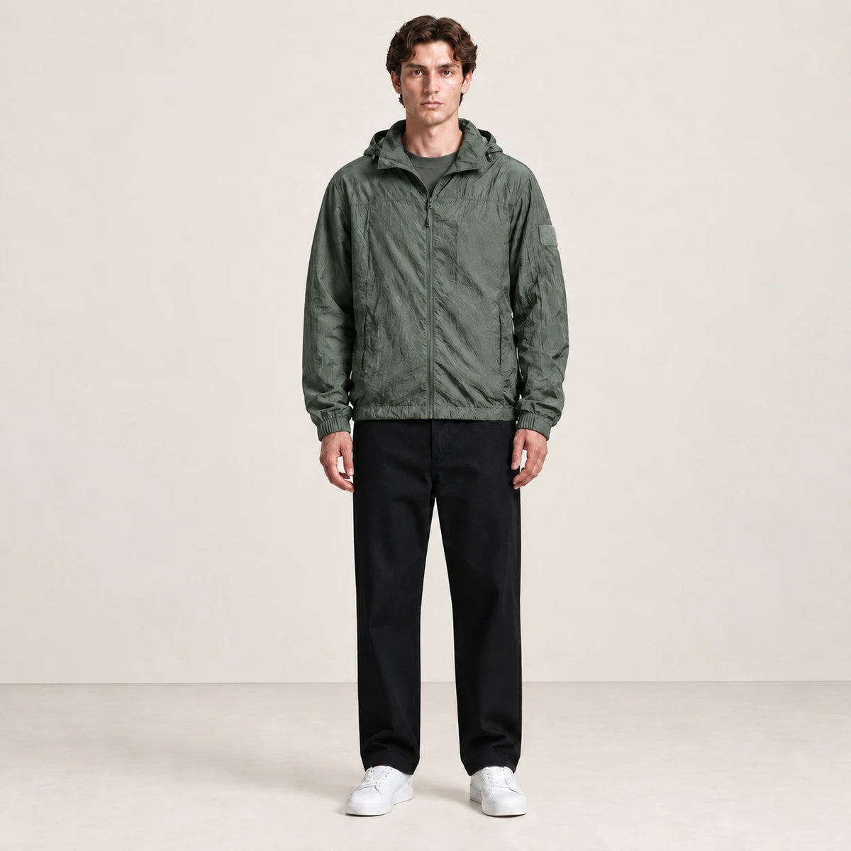 Veste légère verte à capuche et fermeture zippée, portée de face dans le studio IVAREE.